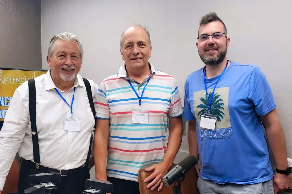 Three men with lanyards pose for a picture looking into camera.