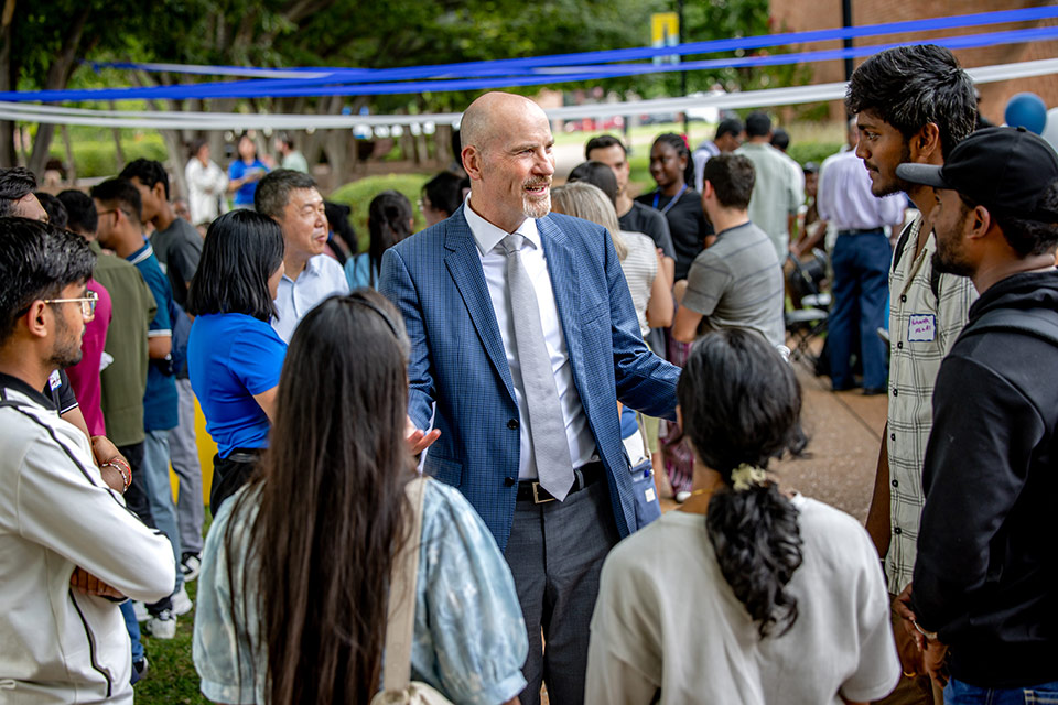 Ed Feser stands and talks amongst a group of students. 